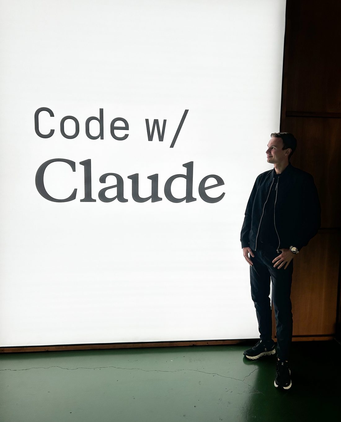 Tomas Parizek standing next to the Code w/ Claude conference sign in London